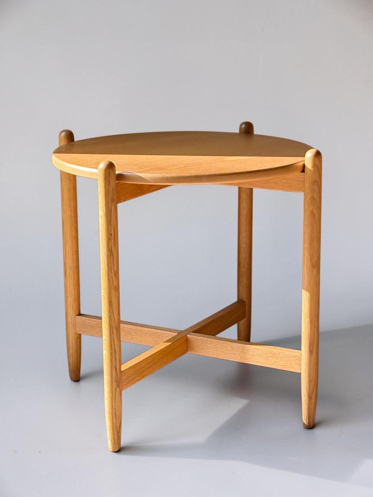 Rundt dansk vintage sidebord i massiv brun eg med skulpturelt krydsstel