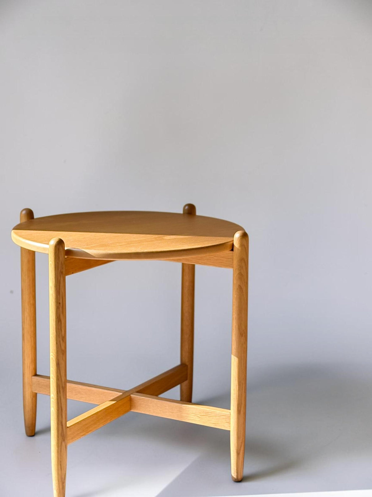 Rundt dansk vintage sidebord i massiv brun eg med skulpturelt krydsstel