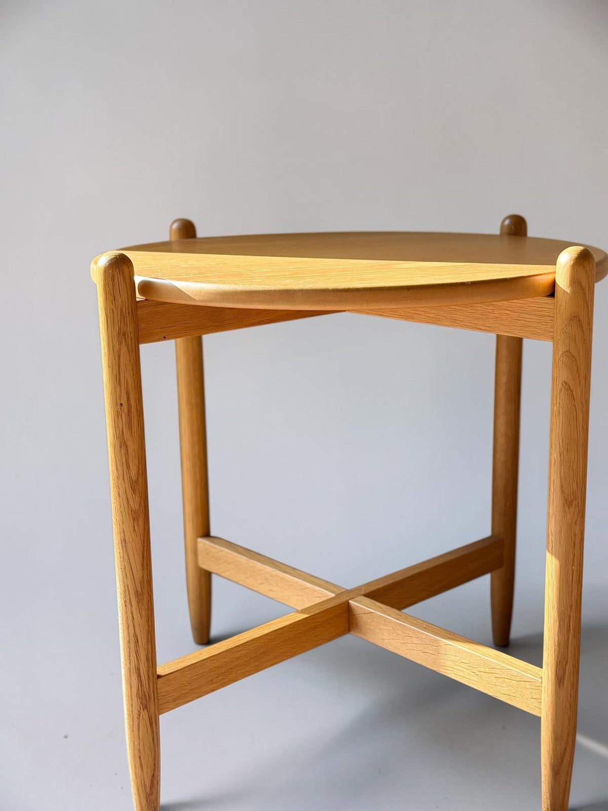 Rundt dansk vintage sidebord i massiv brun eg med skulpturelt krydsstel