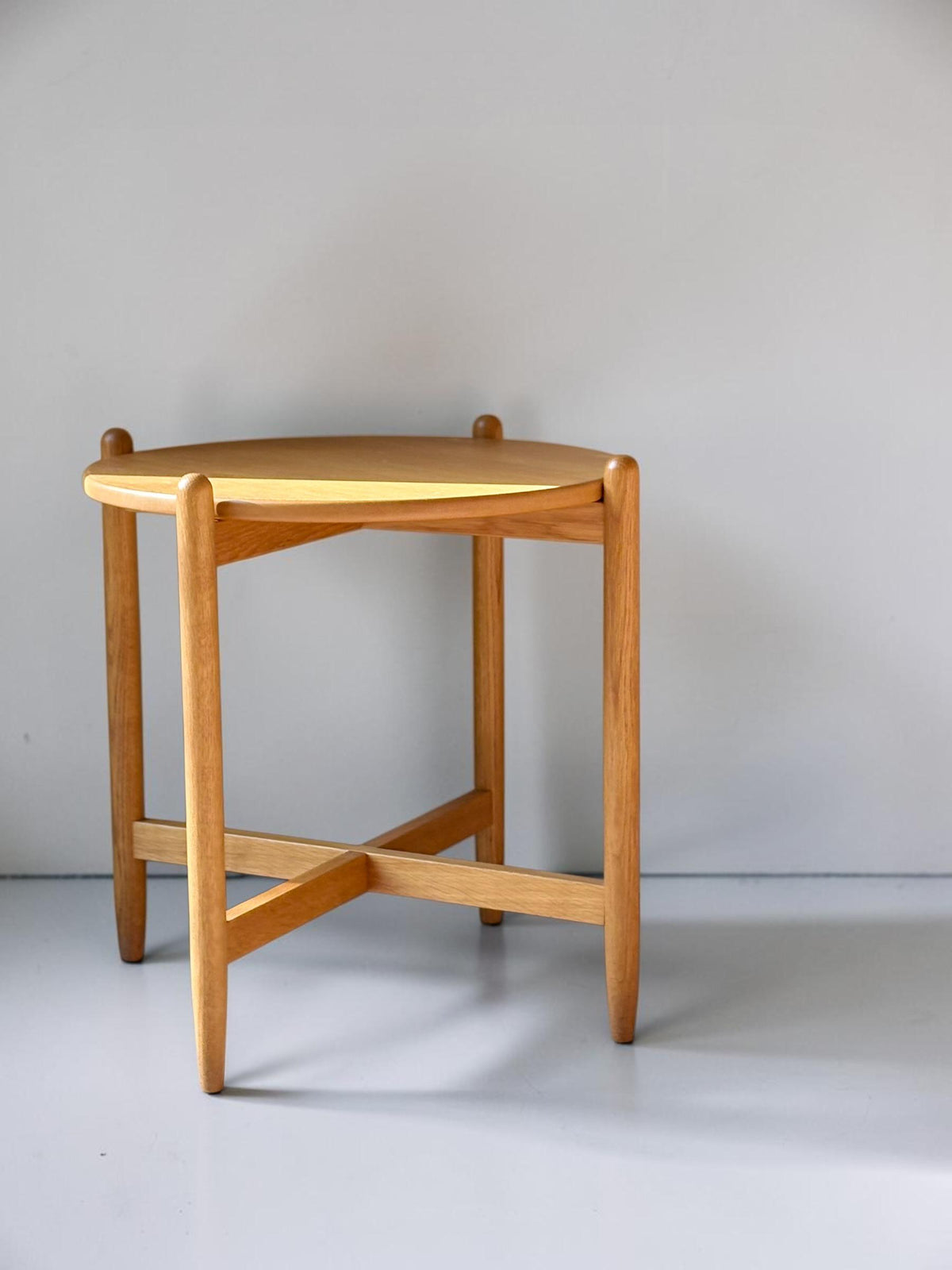Rundt dansk vintage sidebord i massiv brun eg med skulpturelt krydsstel
