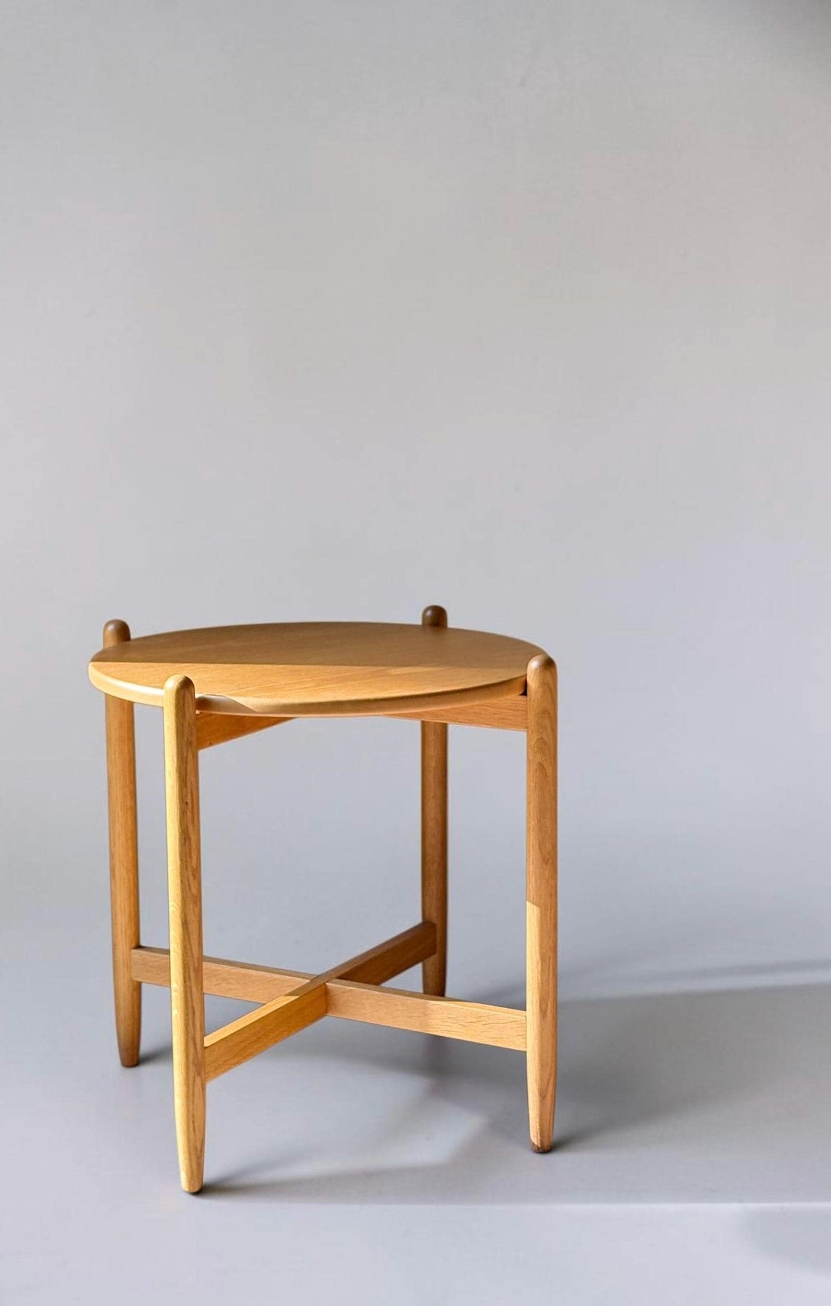 Rundt dansk vintage sidebord i massiv brun eg med skulpturelt krydsstel