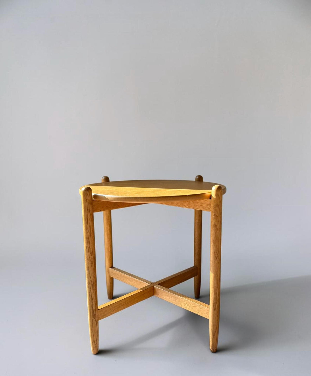 Rundt dansk vintage sidebord i massiv brun eg med skulpturelt krydsstel