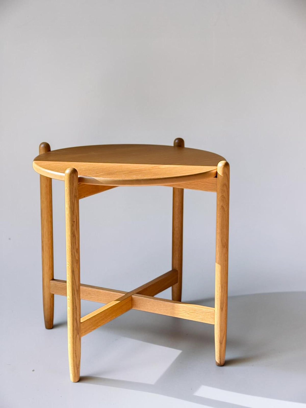 Rundt dansk vintage sidebord i massiv brun eg med skulpturelt krydsstel