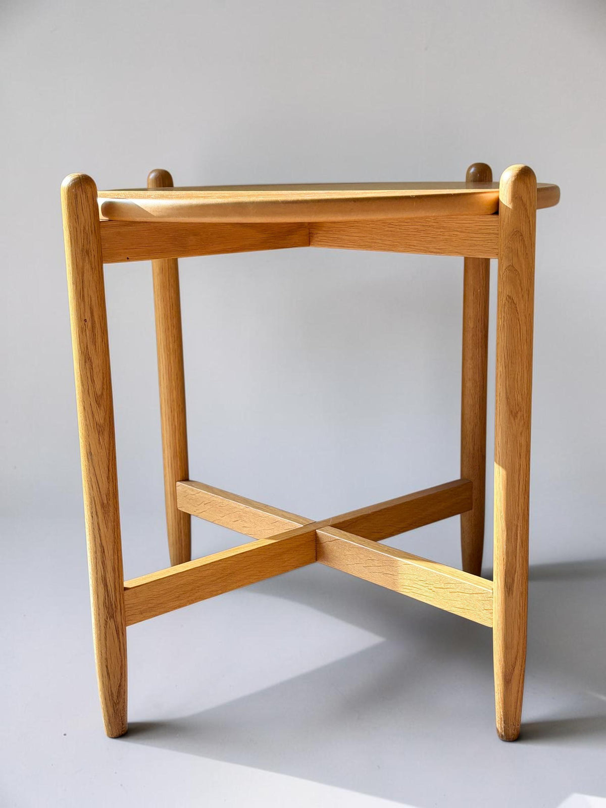Rundt dansk vintage sidebord i massiv brun eg med skulpturelt krydsstel