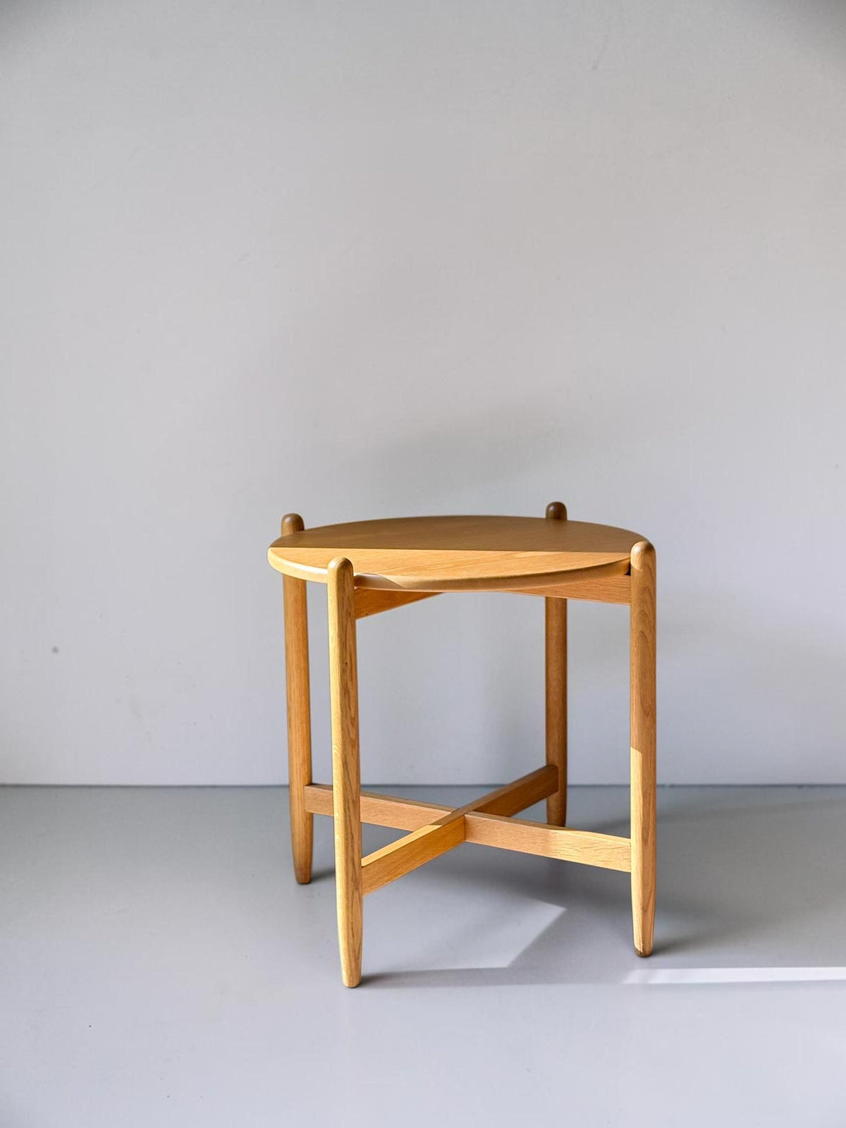 Rundt dansk vintage sidebord i massiv brun eg med skulpturelt krydsstel