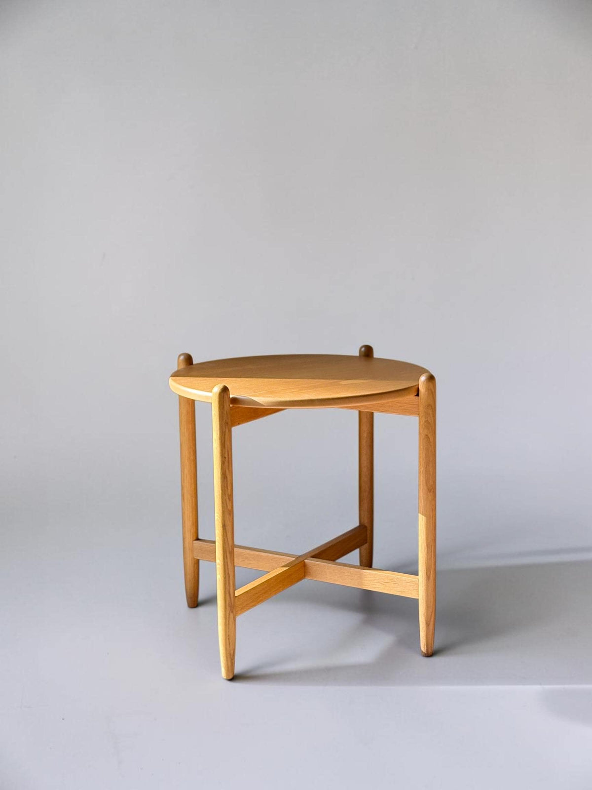 Rundt dansk vintage sidebord i massiv brun eg med skulpturelt krydsstel