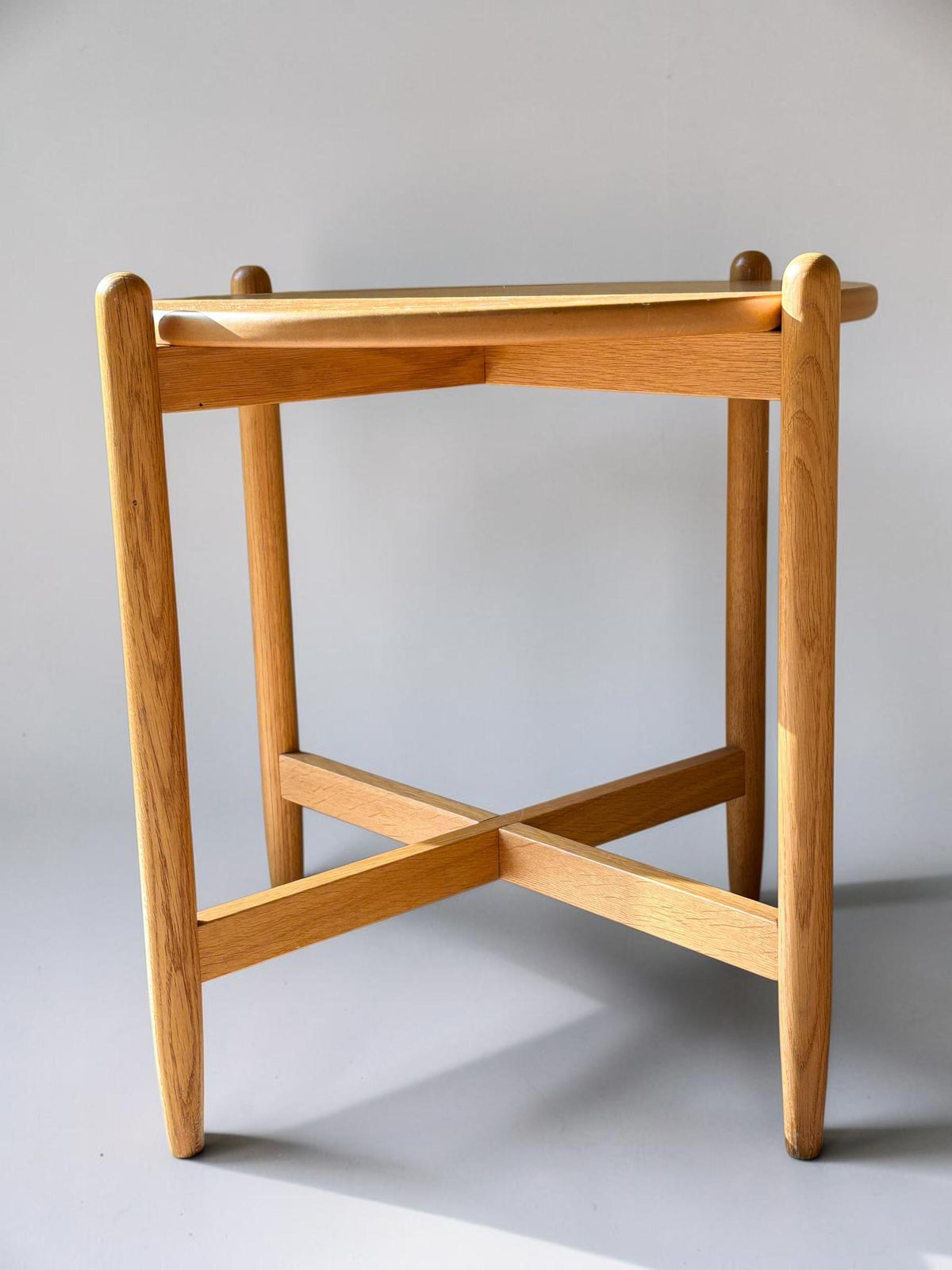 Rundt dansk vintage sidebord i massiv brun eg med skulpturelt krydsstel