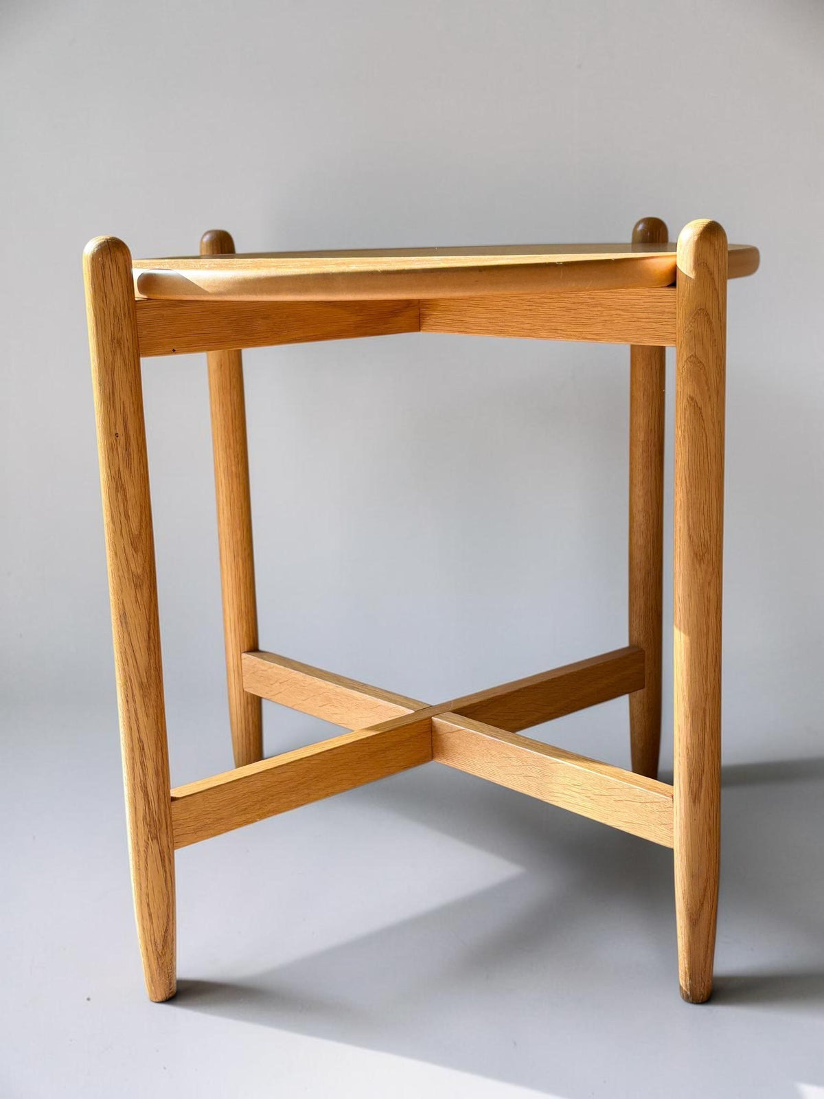 Rundt dansk vintage sidebord i massiv brun eg med skulpturelt krydsstel