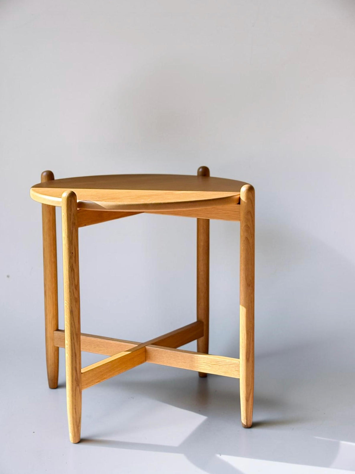 Rundt dansk vintage sidebord i massiv brun eg med skulpturelt krydsstel