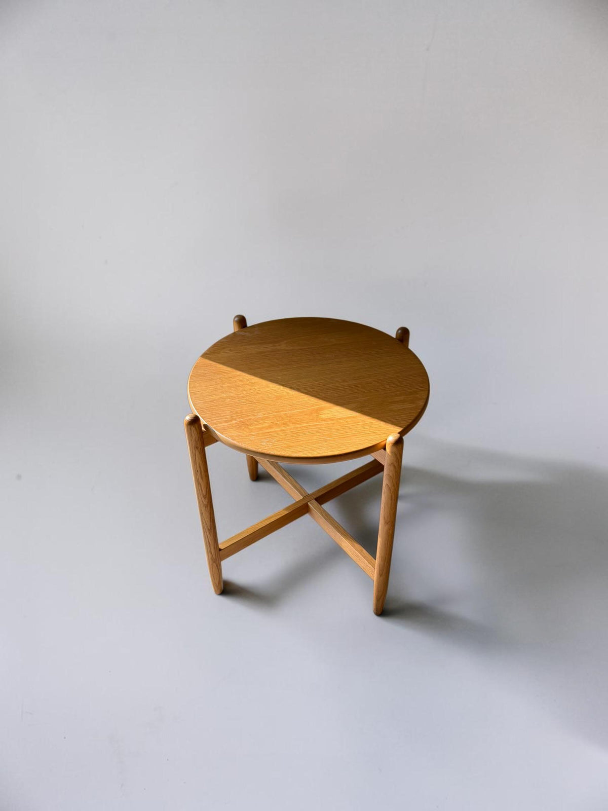 Rundt dansk vintage sidebord i massiv brun eg med skulpturelt krydsstel