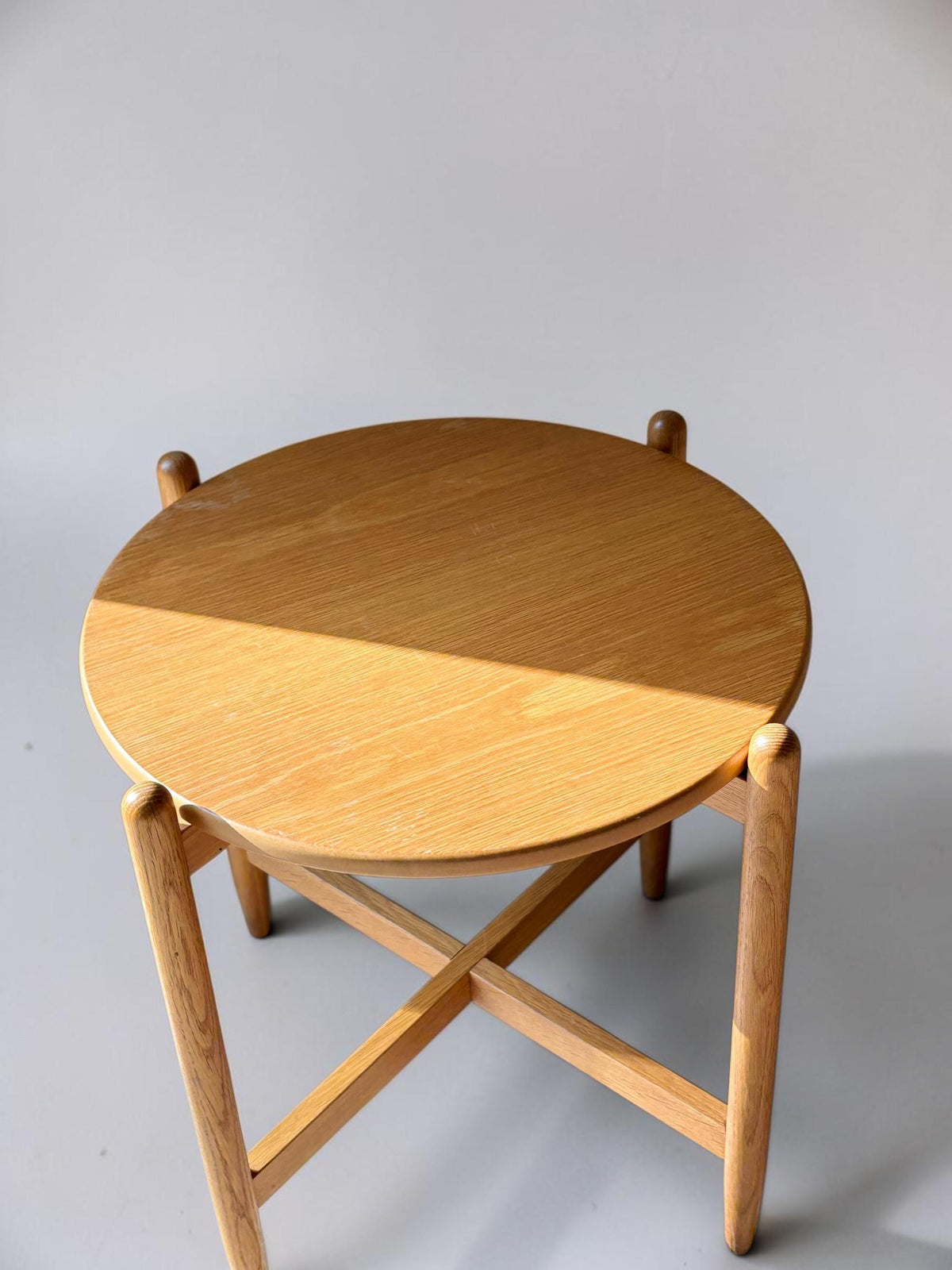Rundt dansk vintage sidebord i massiv brun eg med skulpturelt krydsstel