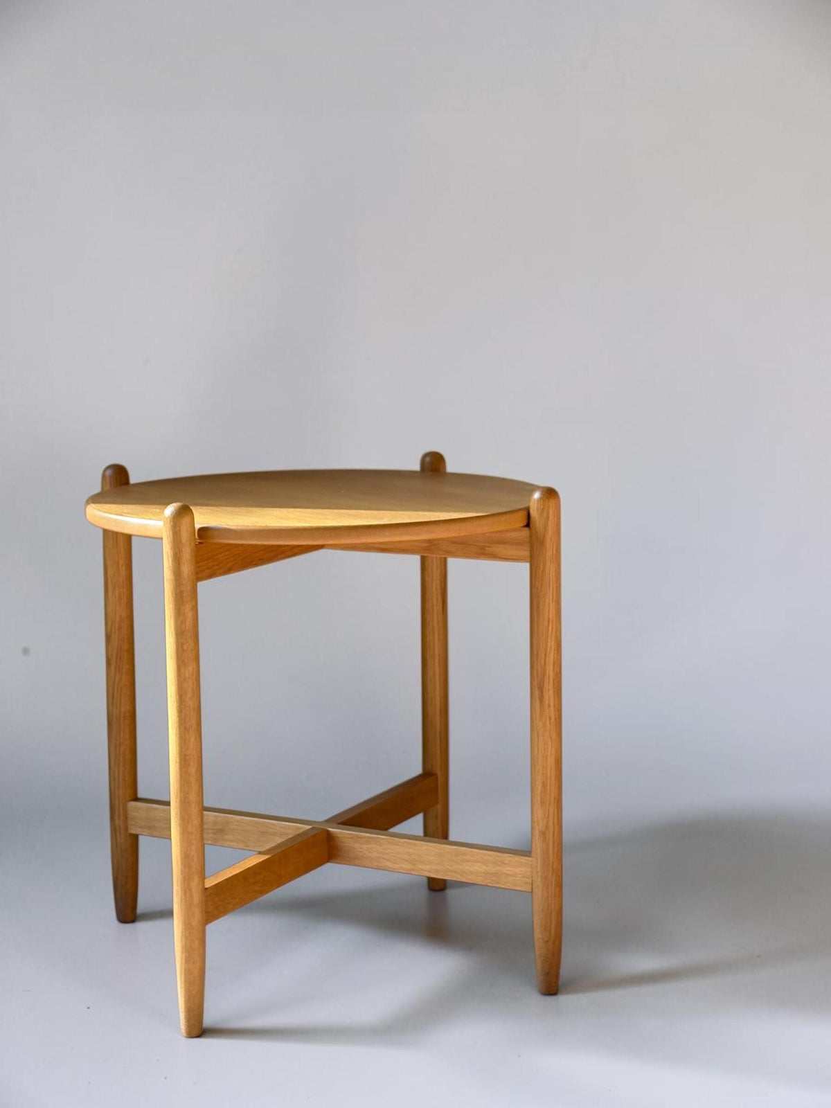Rundt dansk vintage sidebord i massiv brun eg med skulpturelt krydsstel
